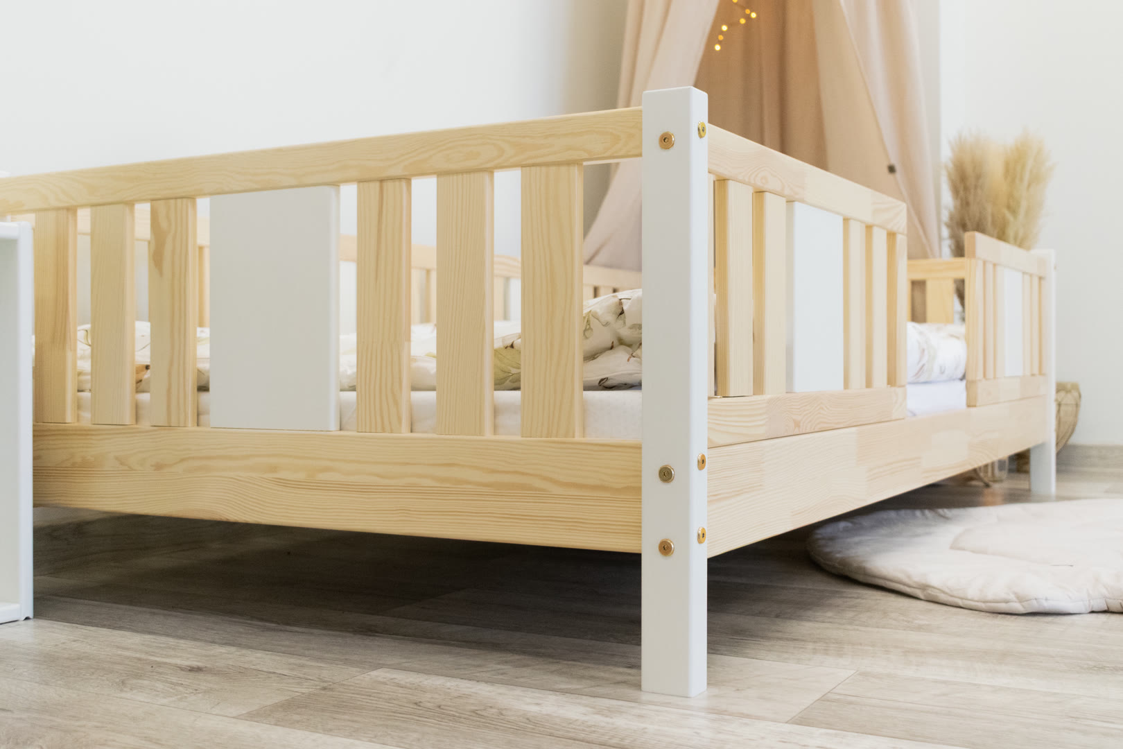 Pojedyncze łóżko z drewna sosnowego w jasnym pokoju dziecięcym z miejscem na biurko obok